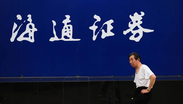 2011年7月26日 在中国东部山东省烟台 一名行人走过海通证券的广告牌 — 图库照片