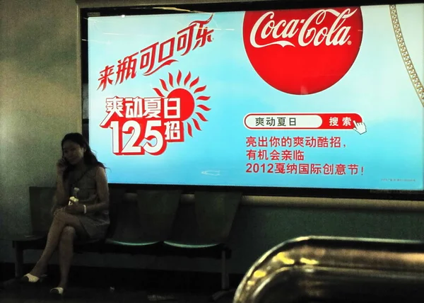 Een Chinese Vrouw Zit Door Een Advertentie Voor Coca Cola — Stockfoto