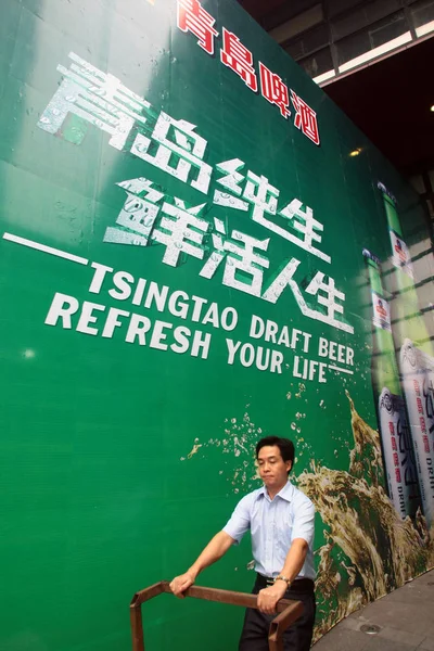 Een Man Loopt Langs Een Advertentie Van Tsingtao Draft Bier — Stockfoto