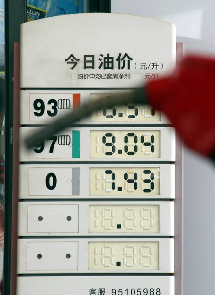 中国の労働者は 海口市のガソリンスタンド 南中国海南州のガスステーションでの更新された燃料価格を示す看板の隣にオイルノズルを保持し 月2011 — ストック写真