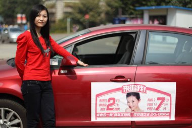 The woman whose Citroen is bedecked with notices with the words husband wanted poses by her car on a street in Changsha, central Chinas Hunan province, 10 October 2011 clipart
