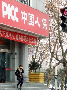 A woman walks out from a branch of PICC in Yichang city, central Chinas Hubei province, 31 January 2011 clipart