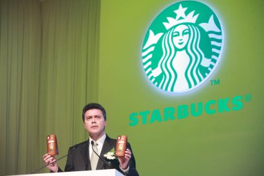 John Culver, President of Starbucks, shows instant coffee packets during a press conference in Beijing, China, March 8, 2011 clipart