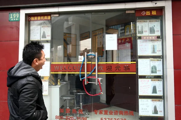 2011年3月3日 一名中国男子走过中国上海一家关闭的房地产中介公司 — 图库照片