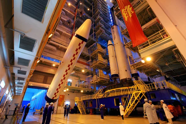 ブースターは Jiuquan 衛星打ち上げセンターの最終組立および試験工場で 長い3月 のキャリアロケットに固定されるように掲揚されています Jiuquan 北西中国甘粛州近く 10月1日2011 — ストック写真