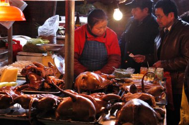 A Chinese vendor sells dog meat to customers at a food market in Guiyang city, southwest Chinas Guizhou province, 20 December 2009 clipart