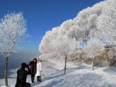 Visitors take photos with the rime scenery in the background by the Songhua River in Jilin city, northeast Chinas Jilin Province, February 6, 2010 clipart