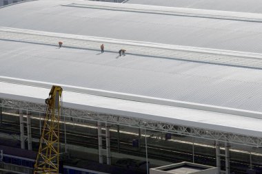 Chinese construction workers walk on the new awnings installed at the Shanghai Railway Station during a renovation project in Shanghai, China, 26 January 2010 clipart