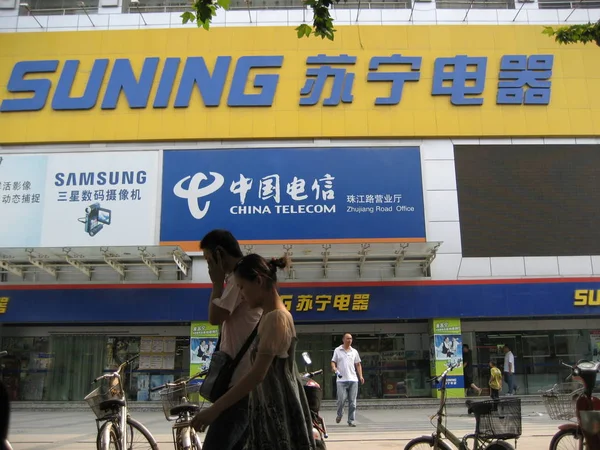 Local residents walk past a retail store of Suning in Shanghai, China, August 24, 2008