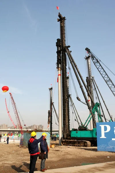 在2011年12月26日于中国上海举行的中国世博会展中心开工典礼上 工人们在建筑机械前观看 — 图库照片