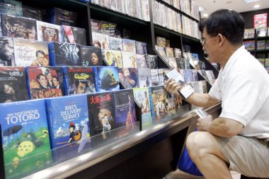A Chinese customer shops for copyrighted DVDs of foreign movies at the Shanghai City of Book in Shanghai, China, 24 September 2009 clipart