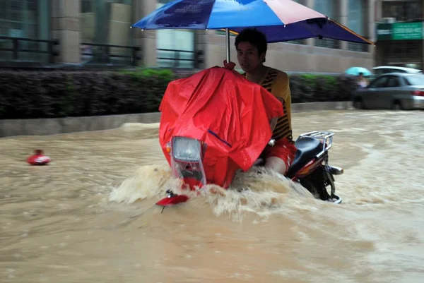 Ένας Άντρας Οδηγάει Μοτοσικλέτα Του Μέσα Από Ένα Πλημμυρισμένο Δρόμο — Φωτογραφία Αρχείου