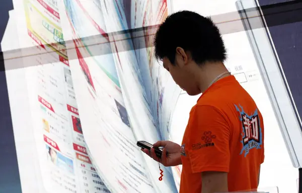中国人従業員は 2009年4月13日 海南省海口市の中国ユニコムの支店で携帯電話を使用しています — ストック写真