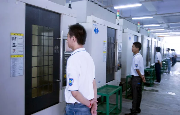中国のフォックスコン労働者は 2010年8月2日 中国河南省中部の浙州市にあるフォックスクーン テクノロジー グループが所有するフー プレシジョン エレクトロニクス Zhengzhou 社の工場の機械の前に立っている — ストック写真