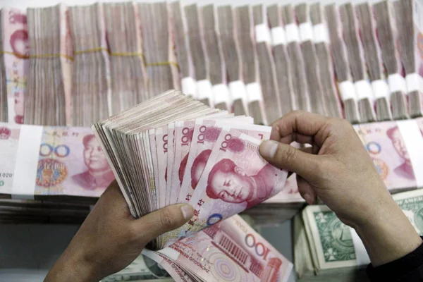 A Chinese bank clerk counts RMB (Renminbi) yuan banknotes at a bank in Huaibei city, east Chinas Anhui province, 22 April 2010