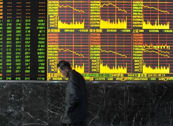 2010年 在中国中部湖北省武汉市的一家股票经纪公司 一位中国投资者走过一块显示股价的董事会 价格上涨为红色 价格下跌为绿色 — 图库照片