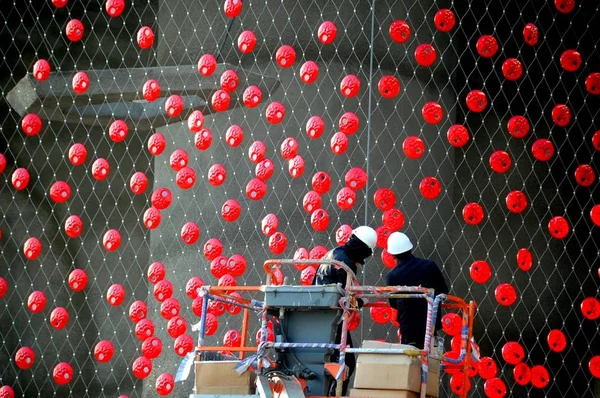 Chinese workers put red decorations on the curtain at Switzerland Pavilion at the Expo site in Shanghai, China, March 16, 2010