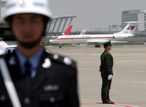 경찰관들이 김영남 조선민주주의인민공화국 최고인민회의 상임위원장을 비행기 근처에서 경비를 있으며 상하이 — 스톡 사진