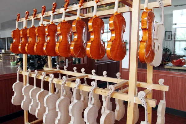 2010年8月12日 北京市東高町にある北京華東楽器株式会社の工場に ハーフフィニッシュと新製のバイオリンが吊り下げられています — ストック写真