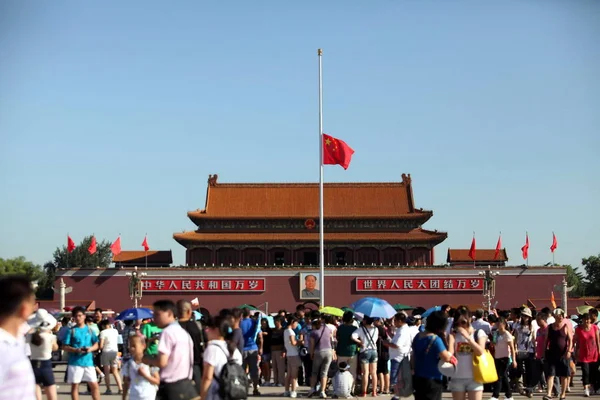 北京の天安門広場で Zhouqu 土砂崩れの犠牲者を弔うため ハーフマストになびく中国国旗を通過する観光客は 2010 月15日 — ストック写真