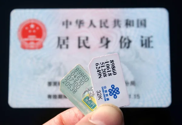 中国の携帯電話ユーザーは 2009年12月22日 中国東部江蘇省蘇州市のIdカードの前にシムカードを表示します — ストック写真