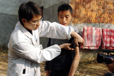 A Chinese doctor examines 19-year-old Wang Jianxue who is the son of He Minggui and suffers from PMD (progressive muscular dystrophy) in Hefan village, Xinzhou district, Wuhan city, central Chinas Hubei province, 16 December 2008 clipart
