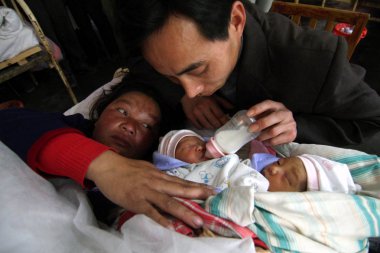 The father of a pair of two-day-old conjoined twin girls feeds them at a hospital in Xinhua county, Loudi city, central Chinas Hunan Province, March 18, 2009 clipart