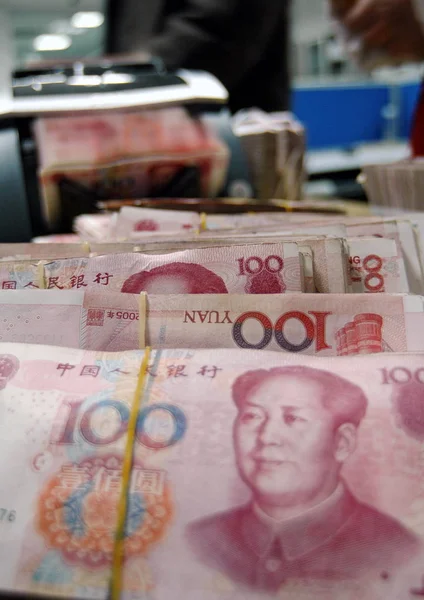 A Chinese bank clerk counts RMB (Renminbi) banknotes at a branch of China Construction Bank (CCB) in Haian county, east Chinas Jiangsu province, January 20, 2009
