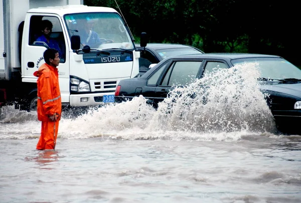 Китайский Рабочий Смотрит Автомобили Проезжающие Затопленной Улице После Сильного Дождя — стоковое фото
