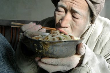 An allegedly-enslaved Chinese mentally handicapped worker eats noodle at a building materials factory in Kumishi town, Toksun county, Turpan, northwest Chinas Xinjiang Uygur Autonomous Region, 11 December 2010 clipart
