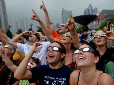 Foreign visitors look through special glasses at the partial eclipse of a total solar eclipse at the Peoples Square in Shanghai, China, Wednesday, July 22, 2009 clipart