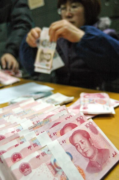 A Chinese bank clerk counts RMB (Renminbi) yuan banknotes at a branch of China Construction Bank (CCB) in Haian county, Nantong city, east Chinas Jiangsu province, 20 January 2009