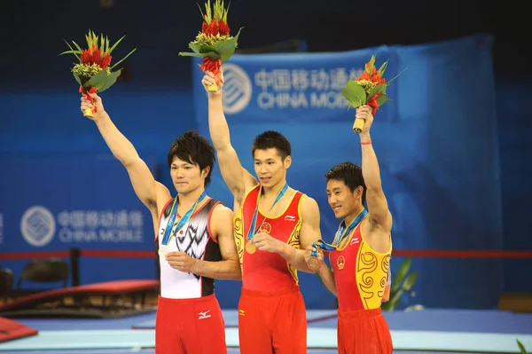 左から 日本の桑原俊選手 銀メダリスト 中国の張成龍選手 金メダリストのテン ハイビン選手が 南Chの広州市で開催された第16回アジア競技大会の男子水平バーの表彰式で表彰台に立ちました — ストック写真