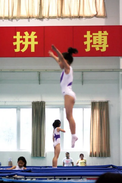 Μικρές Κινεζικές Αθλητές Τραμπολίνο Άσκηση Μπροστά Από Σημεία Που Σημαίνουν — Φωτογραφία Αρχείου