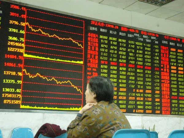 Een Chinese Investeerder Voor Een Tabel Met Het Aandeel Prijzen — Stockfoto