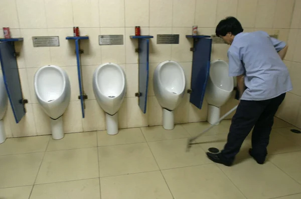 2008年6月25日 北京の公衆トイレ内でクリーナーが床を掃除する — ストック写真
