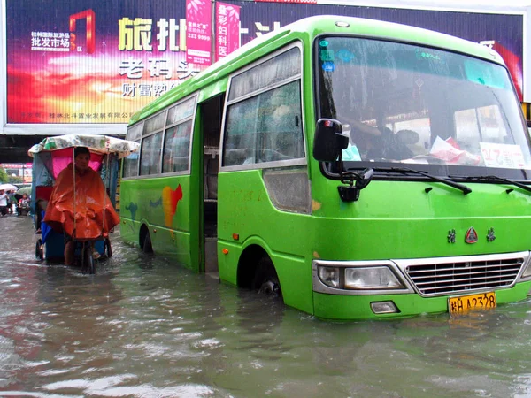 中国のトライサイクリストは 2008年6月12日 中国南部広西チワン族自治区の桂林市で大雨の後 洪水で立ち往生したバスを通り過ぎる — ストック写真