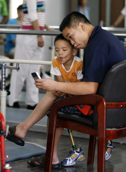 一名中国男子用手机与在四川8 0级地震中失去双腿的儿子合影 现在在成都残疾人康复中心进行恢复训练时 他装备了假肢 — 图库照片