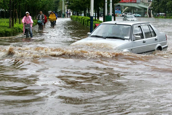 Κινέζοι Ποδηλάτες Και Ένα Αυτοκίνητο Περνούν Μέσα Από Ένα Πλημμυρισμένο — Φωτογραφία Αρχείου