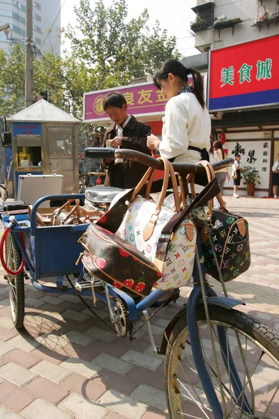 2005年10月24日 一名中国小贩在上海街头销售假冒路易威登 Louisvuitton 的包装袋 — 图库照片