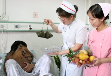 Chinese nurses bring fruits and glutinous rice dumplings to Huang Chuncai, 31, who suffers from huge tumor on the face at Guangzhou Fuda Tumor Hospital in Guangzhou, south Chinas Guangdong province 19 June 2007 clipart