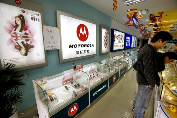 2007년 13일 장쑤성 진장의 휴대전화 가게에서 모토로라 스탠드 근처에서 관리인들이 — 스톡 사진