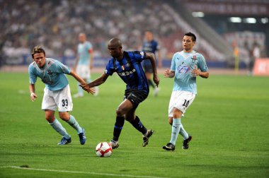 Samuel Etoo Fils of Inter Milan FC, center, breaks through Roberto Baronio, left, and Mauro Matias Zarate, right, of Lazio FC in the final of the Italian Super Cup at the National Stadium, known as the Birds Nest, in Beijing, China, Saturday, 8 Augus clipart