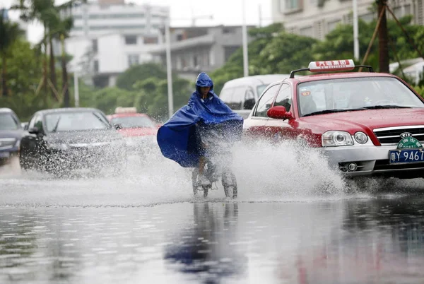 2009年9月15日火曜日 中国南部広東省仏山市の台風コププによる豪雨の後 車は浸水した通りでサイクリストを追い越す — ストック写真