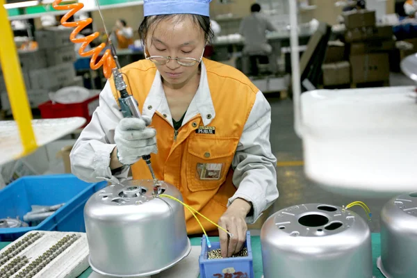 2005年10月25日付けのファイル写真は 中国東部杭州にある浙江省製電機製造有しの子会社である浙江省の電気器具製造有しの工場で電気米鍋を作る中国人労働者を示しています — ストック写真