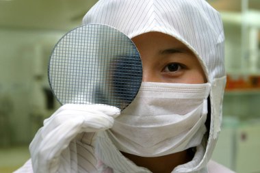 This undated file photo shows a researcher wearing cleanroom suit displaying a wafer in the lab of Shanghai Microsemi Semiconductor Co., Ltd. in Shanghai, China. clipart