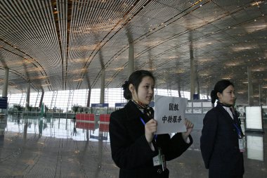 Two airport employees show passengers how to transfer to another airline during an operational drill at the new Terminal 3 of the Beijing Capital International Airport in Beijing, February 23, 2008 clipart