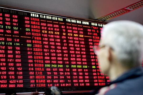 中国の株主は 2007年2月16日に上海の証券取引所ホールで株価 上下に赤 を示す大画面を見ます — ストック写真