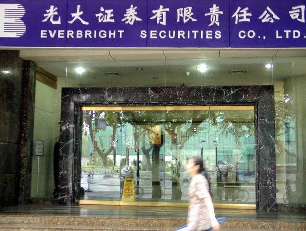未注明日期的照片显示一名中国妇女走过光大证券股份有限公司在上海的一家分行 — 图库照片