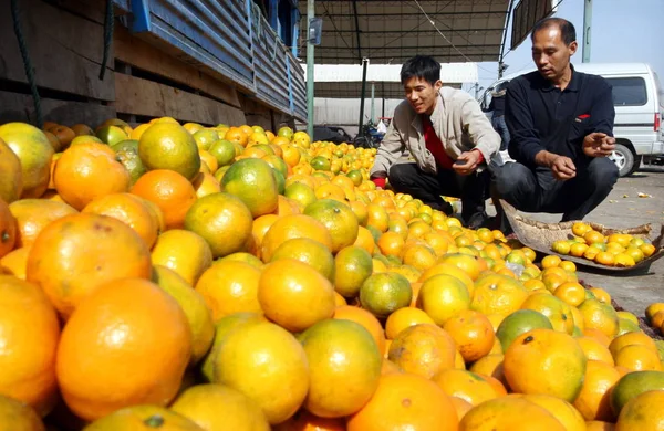 中国のオレンジの売り手は 2008年10月27日 中国東部山東省のWeifang市の果物卸売市場で買い手を待っている間に腐ったオレンジを取り除きます — ストック写真